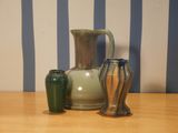 three vases sitting on a table with a striped wall behind them