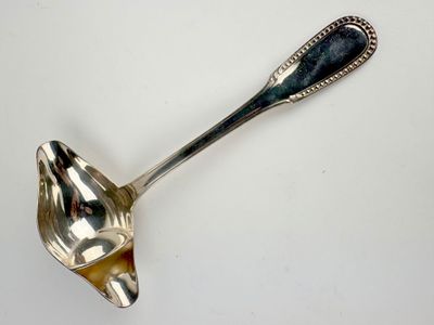 cuillère plaquée argent avec un manche noir sur un fond blanc