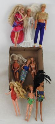 quatre poupées Barbie dans une boîte en carton posée sur une surface blanche