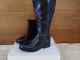 pair of black boots sitting on top of a box on a bed