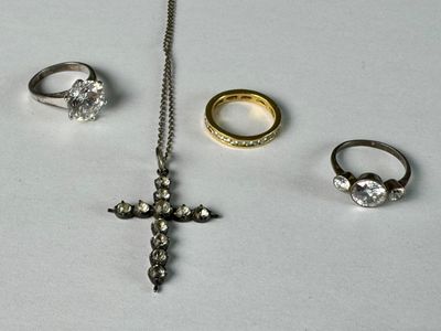 three rings, a cross, and a ring with a chain on a table
