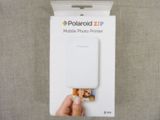 une personne tient dans sa main une imprimante photo portable Polaroid Zip