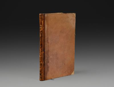 un vieux livre à la couverture brune posé sur une table