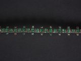 a close up of a bracelet with green beads on a black background