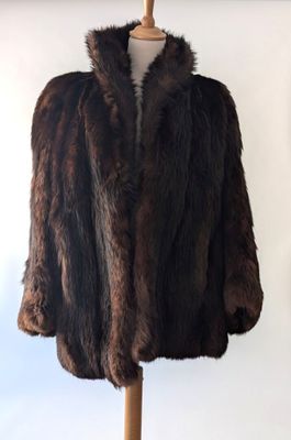 un manteau de fourrure marron posé sur un mannequin, devant un mur blanc