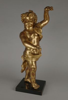 une statue en or représentant un enfant tenant un oiseau, posée sur un socle noir