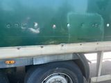 a green semi truck with a flat bed on the back