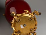 a red and gold clock sitting on a white surface