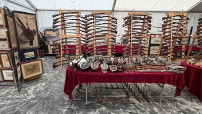 une table recouverte d'une nappe rouge sur laquelle sont posées plusieurs armes à feu
