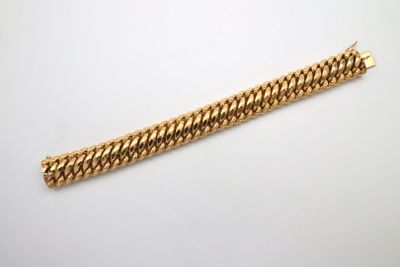 gros plan d'un bracelet en or sur une surface blanche
