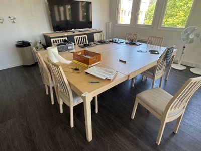 une table en bois avec des chaises et une télévision dans la pièce