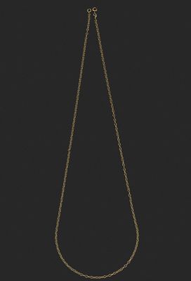 un collier en or dont la chaîne a été coupée en deux et qui est posé sur un fond noir