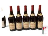 six bottles of wine are lined up in a row on a white surface