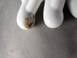 two white vases with flowers on them sitting on a table