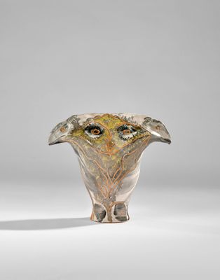 un vase en verre orné d'un visage, posé sur une table