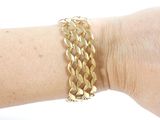 a woman ' s arm with a gold bracelet on it