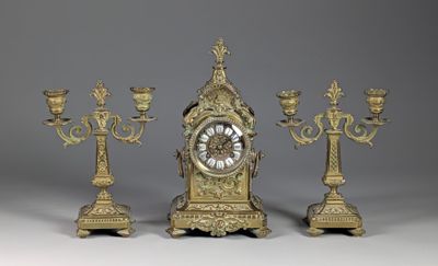 three candles and a clock sitting on a table