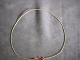 a picture of a gold plated necklace with a red bead