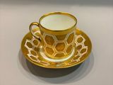 une tasse à café jaune et blanche avec sa soucoupe, posée sur une table blanche