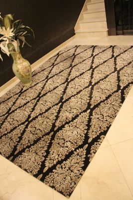 un tapis noir et blanc sur lequel est posé un vase de fleurs