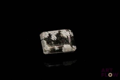 une image représentant une pierre noire et blanche posée sur une surface noire