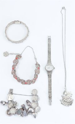 a lot of silver jewelry on a white surface