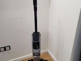 the vacuum is sitting on the floor in the corner of the room
