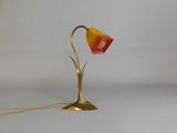 brass table lamp with a red and yellow shade on a white background