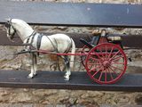 a white horse pulling a red carriage on a bench