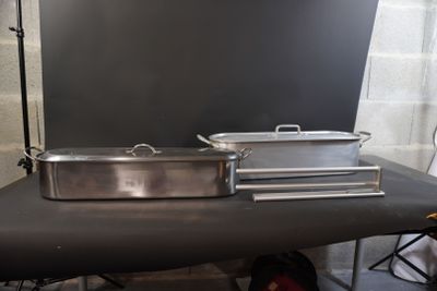 two pans sitting on a table in front of a backdrop