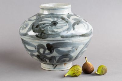 un vase bleu et blanc, avec une figurine à côté