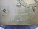 a close up of a metal clock with writing on it