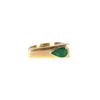 gros plan d'une bague en or avec une pierre verte