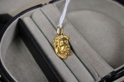a gold pendant with a face on it in a case