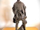 une statue en bronze représentant un garçon avec un chien, posée sur une table