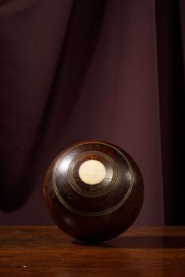 une boule en bois posée sur une table en bois, à côté d'un rideau