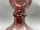 a pink glass vase with a bird on top of it