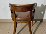 a wooden chair with a brown leather seat on a tiled floor