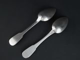 two silver spoons on a black surface with a black background