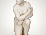 a white marble statue of a boy kneeling on a pedestal