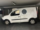 une camionnette blanche garée dans un garage, avec une pancarte sur le côté du véhicule