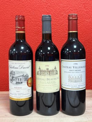 three bottles of red wine sit on a table in front of a red wall