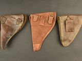three leather holsters on a gray surface