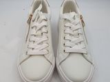 les baskets blanches sont posées sur une surface blanche, devant un fond blanc