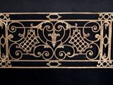 une grille de cheminée ancienne en fonte, ornée de volutes