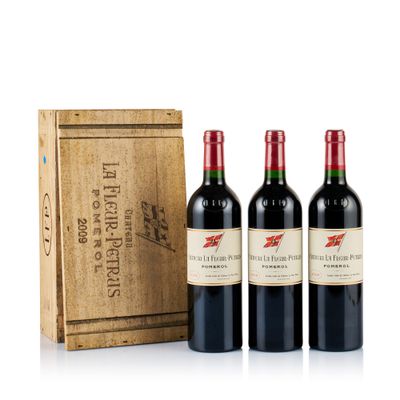 trois bouteilles de vin rouge devant une caisse en bois