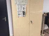 a tall cabinet in the corner of a room next to a door