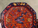 une assiette décorative sur laquelle est représenté un oiseau, posée sur une table