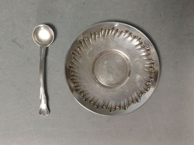 une assiette en argent avec une cuillère et un repose-cuillère posés sur une table