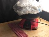 un objet rouge posé sur une table en bois, recouvert d'un sac en plastique